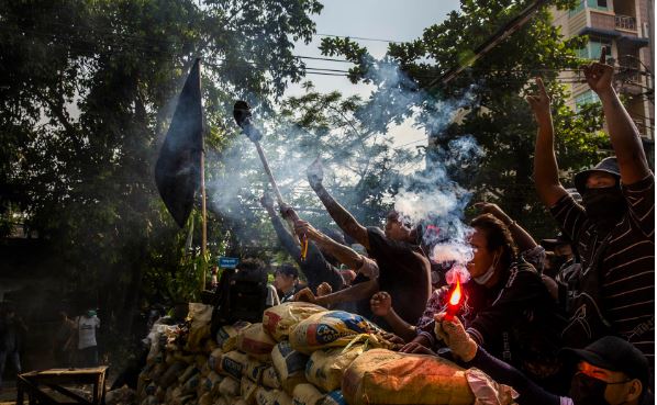 Protesters shout at security forces from behind a makeshift barrier in the Thaketa Township of Yangon, Myanmar, March 28, 2021. (The New York Times) In Myanmar, Sham Elections Aren’t the Path to Stability